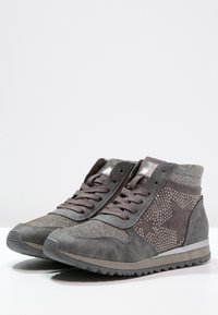 Šedé vysoké tenisky s kombinací semiše a metalických akcentů, zdobené hvězdnými vzory a texturovaným pleteným límcem. Gumosole.