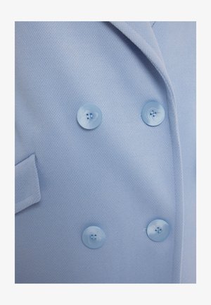Jasnoniebieska dwurzędowa marynarka wykonana z fakturowanej tkaniny, z dużymi dopasowanymi guzikami i jedną kieszenią.