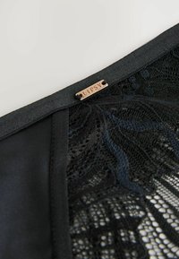 Zwarte lingerie met een kanten paneel en satijnen afwerking. Een klein metalen label met de tekst "LIPSY" is aan de bovenrand bevestigd.