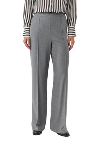 Szare spodnie o szerokich nogawkach z teksturowanej tkaniny, z przodu posiadają zakładki i wysoki stan, zestawione z koszulą w paski z długim rękawem.