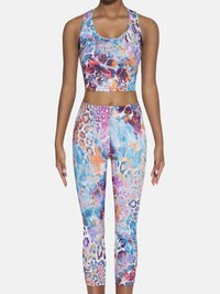 Wielokolorowy zestaw sportowy z krótkim topem i dopasowanymi legginsami 7/8. Wzór zawiera żywe plamy niebieskiego, pomarańczowego i fioletowego w stylu lamparta.