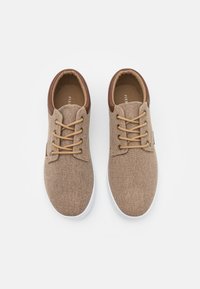 Brown fabric sneakers with a textured finish, contrasting brown leather accents, white rubber soles, and beige laces. Top view.