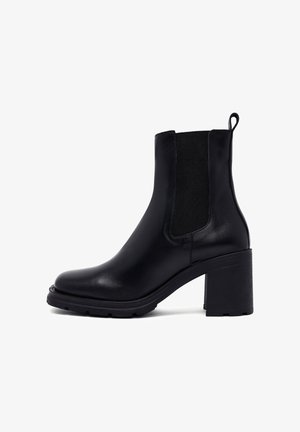 Zwarte leren enkelboots met een ronde neus, elastische zijpanelen en een blokhak. Beschikt over een gestructureerde zool voor grip.