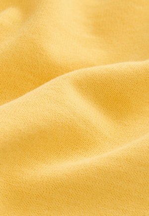 Tissu jaune avec une texture lisse et un motif de tricot fin, affichant des variations subtiles de couleur et de détails de surface.