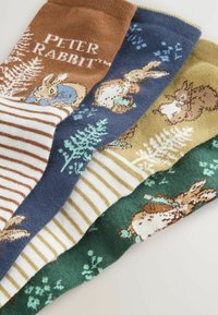 Ensemble de quatre chaussettes : marron avec texte et motifs blancs, marine avec des lapins, vert avec du feuillage et or avec des motifs de lapin et de fleurs.