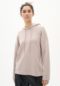 Felpa rosa chiaro con cappuccio, design oversize, maniche lunghe e dettagli con lacci. Texture liscia, polsini e orlo a coste.