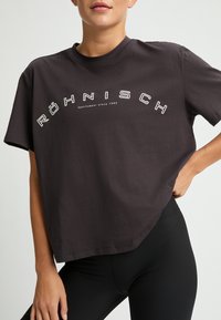 T-shirt in cotone nero con una vestibilità rilassata, caratterizzato da una scritta bianca "Röhnisch Sportswear dal 1945" sul petto. Maniche corte, scollo rotondo.