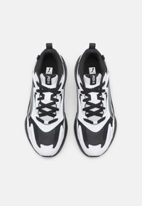 Svartvita sportskor med en texturerad ovandel, kontrasterande paneler, vadderad krage och svarta snörningar. Har en framträdande logotyp på fliken.