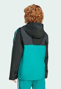 Svart och teal jacka med huva, med en färgblockdesign och elastiska ärmar. Slät, vattenavvisande tyg med en avslappnad passform.