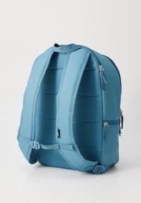 Μπλε σακίδιο που αποτελείται από υφασμάτινη υφή, διαθέτοντας επενδεδυμένους ιμάντες ώμου, λαβή στην κορυφή και δύο πλαϊνές τσέπες με φερμουάρ.