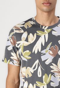 Tricou cu mânecă scurtă, guler rotund, cu imprimeu floral în gri închis, având modele abstracte de flori în nuanțe de crem, verde și maro pe o țesătură moale.
