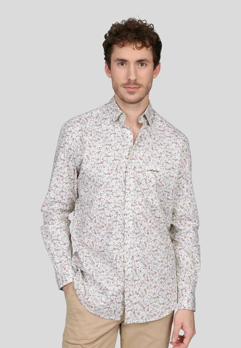Chemise blanche avec motif floral coloré, col à boutons, manches longues, poche poitrine et ourlet légèrement arrondi. En coton.