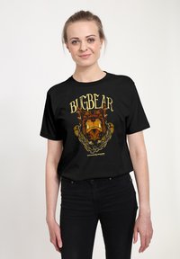 Černé bavlněné tričko s grafickým potiskem hlavy medvěda a zlatým nápisem "BIGBEAR" nad ním, obklopeným dekorativním rámem.