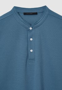 Polo a maniche corte blu realizzato in tessuto testurizzato, con una patta a tre bottoni e colletto tondo. Etichetta con la scritta "CALLIOPE", taglia L.
