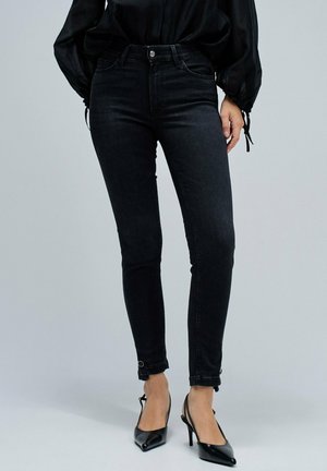 Jeans skinny negros con una textura de denim suave, tiro alto y botones en la parte frontal; el dobladillo presenta bucles únicos para un ajuste ajustable.
