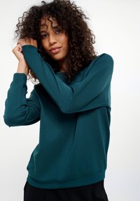 Teal lange mouw sweatshirt gemaakt van zachte stof met een relaxte pasvorm. Heeft subtiele stiksels en een ronde halslijn.