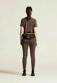Athletic outfit featuring a fitted brown t-shirt and matching leggings, with a black fanny pack accented by yellow detailing.