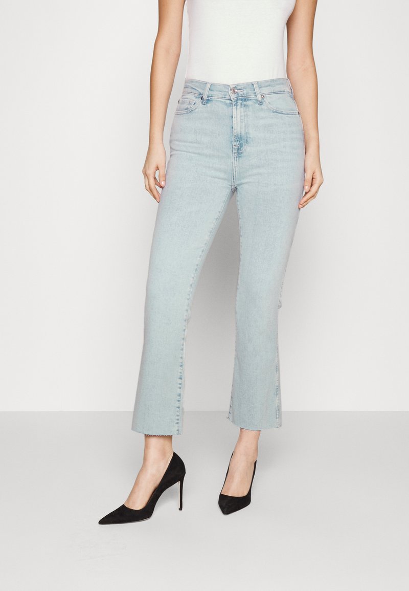 Lyseblå cropped jeans med en frayed kant, høj talje-design og en klassisk fem-lommes stil, parret med sorte spidse hæle.