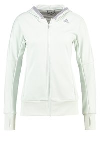 Sweat à capuche Adidas blanc à fermeture éclair complète, avec des trous pour les pouces dans les manches et une doublure en mesh gris à l'intérieur de la capuche, vue de face.