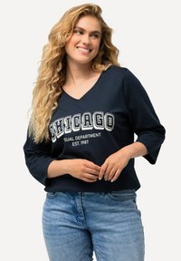 Navyblaues V-Ausschnitt-T-Shirt mit "CHICAGO VISUAL DEPARTMENT EST. 1987" in Weiß bedruckt, mit Dreiviertelärmel und lässiger Passform.