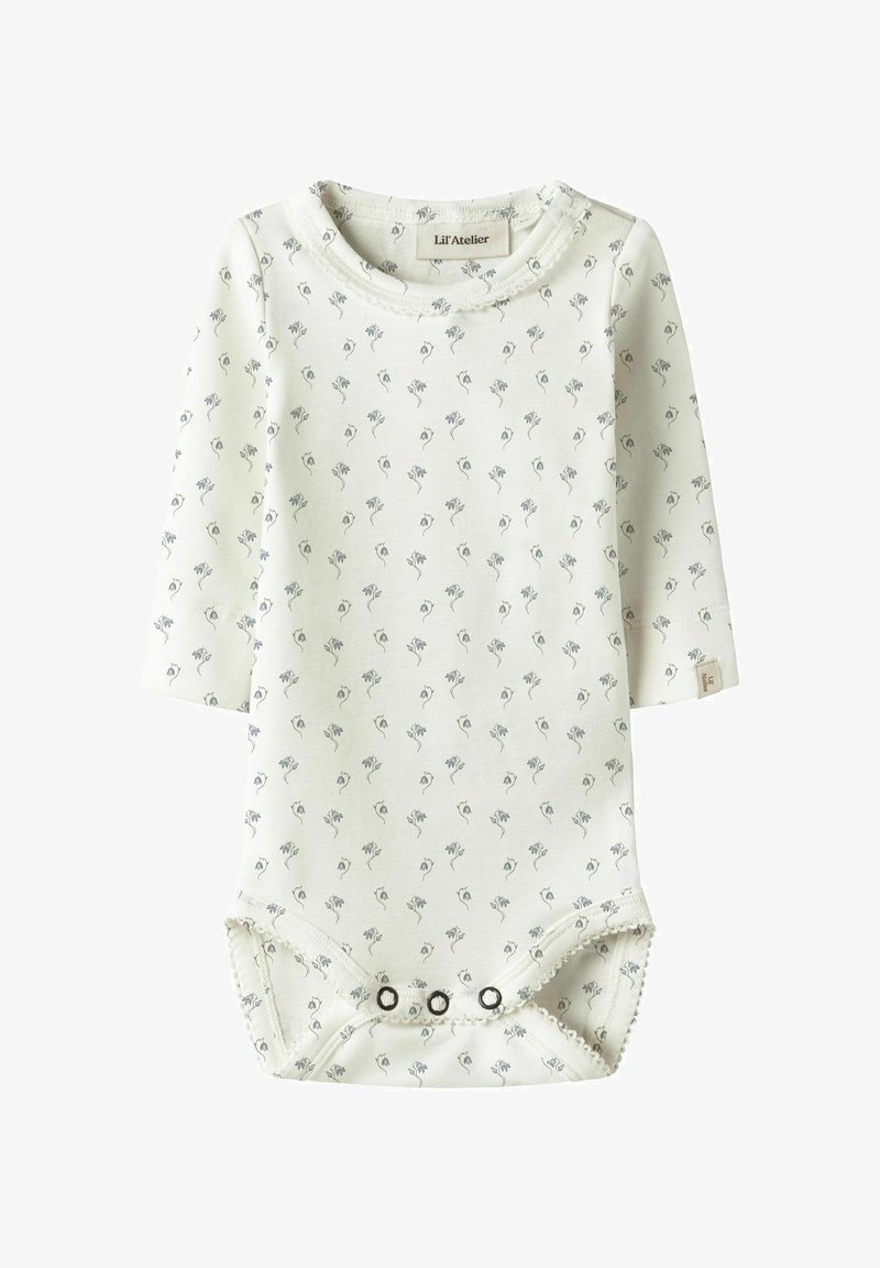 Hvit langermet body med små grå blomsterprint. Den har rund hals og knapper i bunnen for enkel påkledning. Mykt stoff.