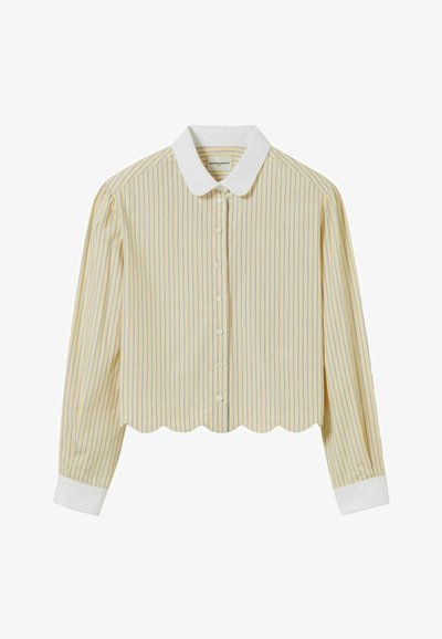 Chemise cropped en tissu léger, avec des rayures verticales jaunes et bleues, un ourlet festonné blanc et un col blanc avec des boutons.