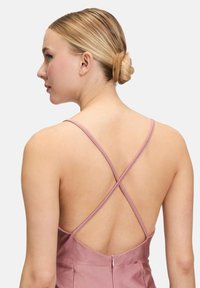 Robe en satin rose avec un dos décolleté et des bretelles croisées. Présente une fermeture éclair dissimulée et une texture lisse, mettant en valeur des lignes et une silhouette élégantes.