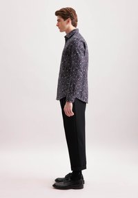 Camicia a maniche lunghe blu navy con motivo floreale; vestibilità slim. Abbinata a pantaloni neri sartoriali e scarpe eleganti nere.