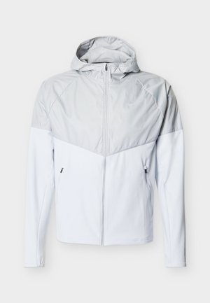 Φωτεινό γκρι μπουφάν με κουκούλα και εμπρός φερμουάρ, αντίθετο πάνω π άνελ, δύο πλαϊνές τσέπες και λεία υφή.