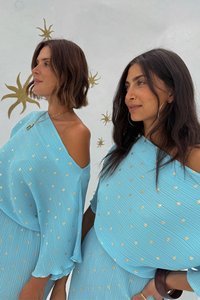 Lichtblauwe geplooide jurken met off-shoulder mouwen, accentueert door gouden stippen. De stof lijkt zacht en textuur te hebben, met een relaxed fit.