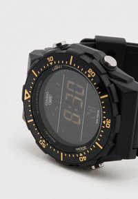Cyfrowy zegarek z czarnym gumowym paskiem, czarną tarczą i pomarańczowymi akcentami. Wyposażony w funkcję podświetlenia oraz wodoodporność do 100 metrów.