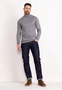 Grå rullekrave sweater, mørkeblå slim-fit jeans, brune ankelstøvler. Klassisk design, blød tekstur, figursyet form, opsmøgede jeans.