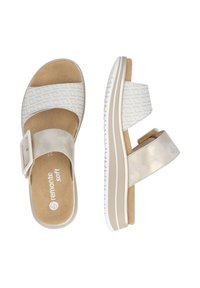 Sandales bicolores avec une tige en tissu crème texturé, une bride métallique et une semelle intérieure beige rembourrée. Présente une semelle blanche contrastante.