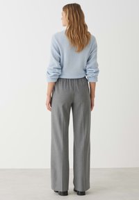 Light blue sweater with rolled cuffs paired with gray wide-leg trousers. Smooth texture, relaxed fit, elastic waistband, and straight silhouette.