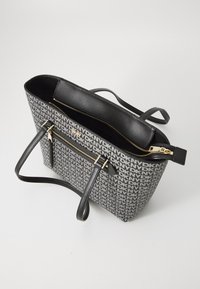 Black and gray tote bag with a canvas exterior featuring repeated logo pattern, two shoulder straps, and gold zipper detailing.