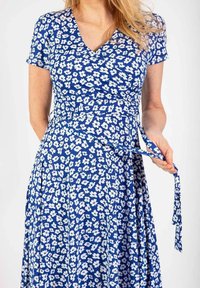 Niebieska sukienka w kwiaty z krótkimi rękawami, dekoltem w serek oraz białymi wzorami kwiatowymi, z wiązaniem w talii i zwiewnym dołem.