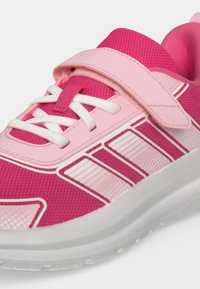 Scarpetta da bambino rosa e rosa chiaro con lacci bianchi, striscia in velcro, strisce laterali decorate e suola in gomma bianca.