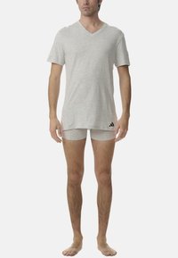 Szary t-shirt w serek oraz dopasowane majtki wykonane z miękkiej, teksturowanej tkaniny. Koszulka ma delikatnie zaokrąglony dół oraz logo adidas na dole.