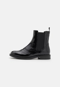 Black patent leather Chelsea boots with elastic side panels, brogue detailing, rounded toe, and a low block heel.