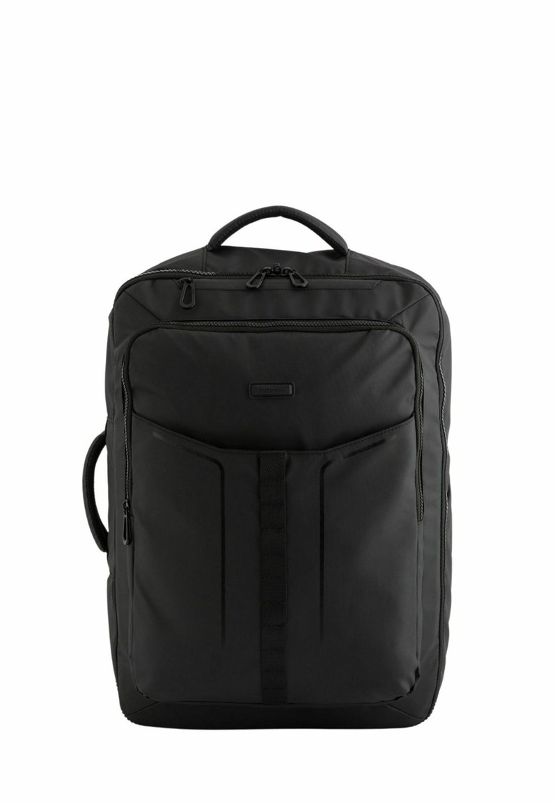 Mochila negra con superficie de tela suave, dos compartimentos con cremallera, un asa en la parte superior y detalles de cinta en la parte frontal para almacenamiento adicional.