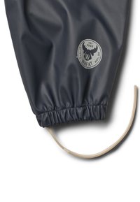Manchette imperméable foncée avec un poignet élastique et un cordon beige, avec un logo circulaire représentant des bois d'élan et le texte "Wheat Danish Design est 2002".