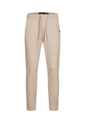 Pantalon de survêtement beige fuselé avec taille élastique et cordon de serrage, orné d'une petite étiquette de logo sur le côté.
