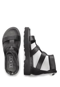 Sandali di pelle nera con ampie cinghie multiple, suola testurizzata e cerniera laterale per la chiusura. Design sagomato con soletta imbottita.