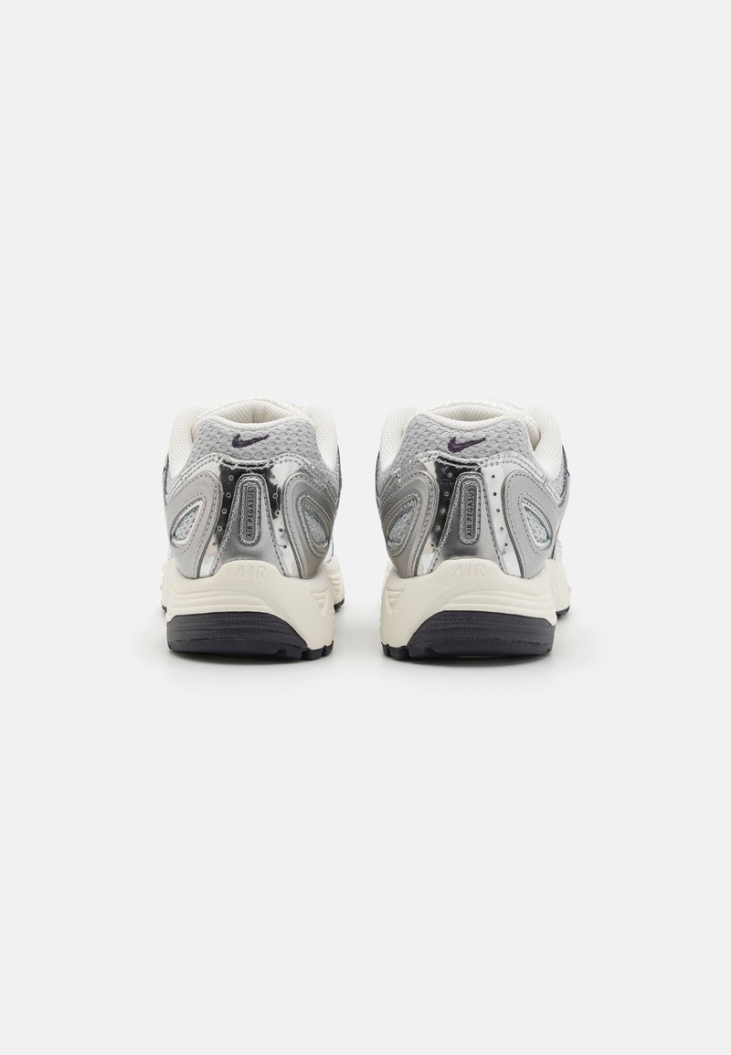 Zapatillas deportivas blancas y grises con un upper de malla texturizada, acentos plateados y una suela negra. Presentan un collar acolchado y detalles reflectantes.