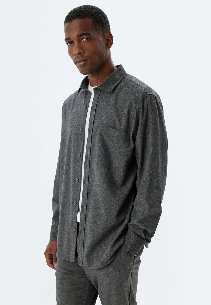Camisa de botones de manga larga en gris oscuro, hecha de una tela texturizada, con un bolsillo en el pecho, un cuello clásico y un ajuste relajado.