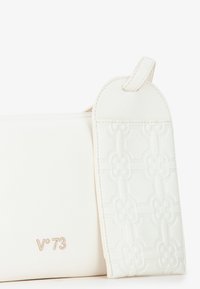 Borsa a tracolla bianca in pelle con motivo floreale in rilievo e un'etichetta piatta e tondeggiante. Presenta un sottile logo del marchio in oro chiaro sul fronte.