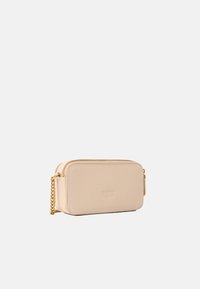 Borsa a tracolla in pelle beige con tracolla in catena dorata, chiusura con zip, forma rettangolare e logo stampato sul pannello anteriore.