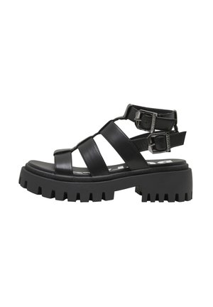 Black chunky sole sandal with three wide leather straps and two adjustable buckles around the ankle.