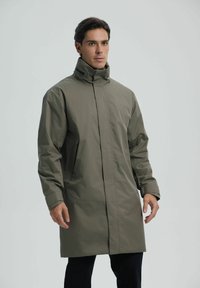 Oliwkowy, wodoodporny, długi płaszcz z wysokim kołnierzem i ukrytym zamkiem błyskawicznym z przodu. Posiada długie rękawy i boczne kieszenie.