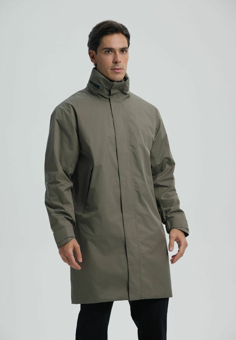 Oliwkowy, wodoodporny, długi płaszcz z wysokim kołnierzem i ukrytym zamkiem błyskawicznym z przodu. Posiada długie rękawy i boczne kieszenie.